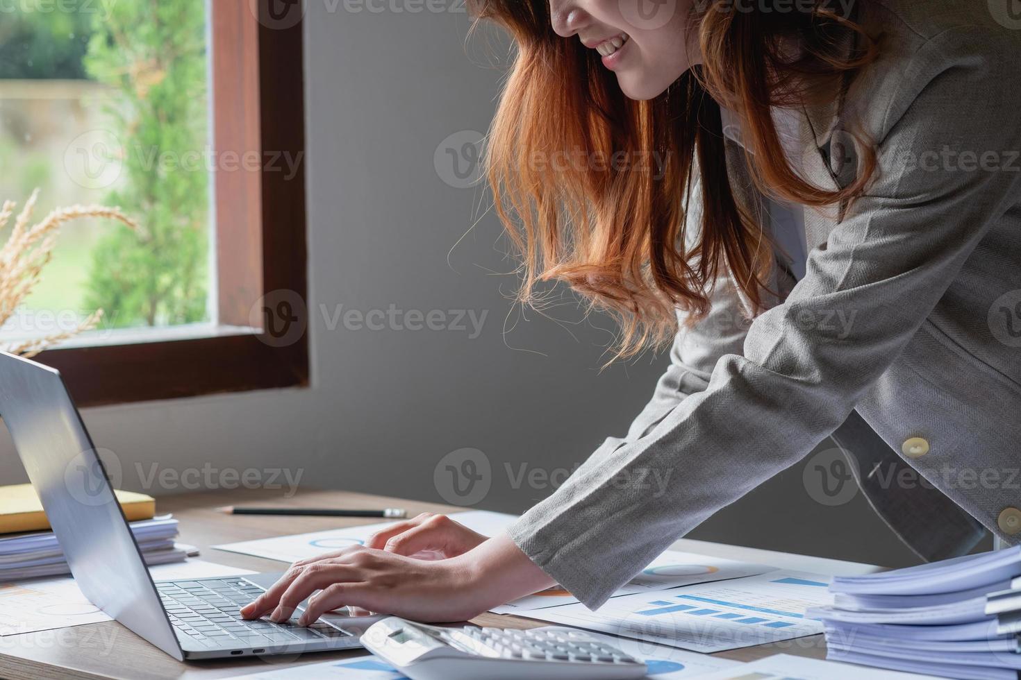 marketing, finanzen, buchhaltung, planung, geschäftsfrauen analysieren unternehmensergebnisse und gewinne mit grafikstatistiken. Verwenden Sie einen Laptop-Computer und einen Taschenrechner, um die Bilanz des Unternehmens zu berechnen. foto