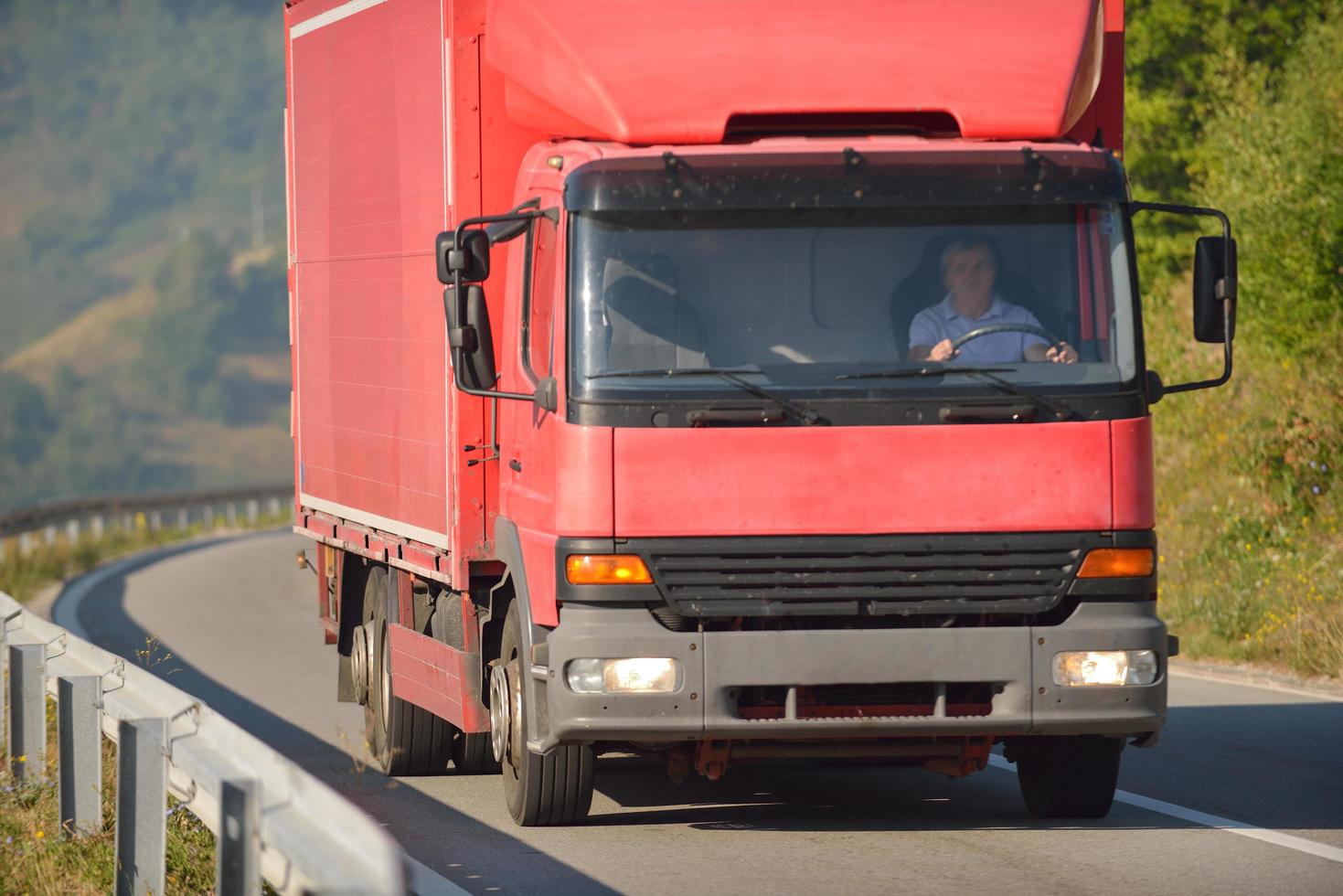 roter lkw, der auf asphaltstraße fährt foto