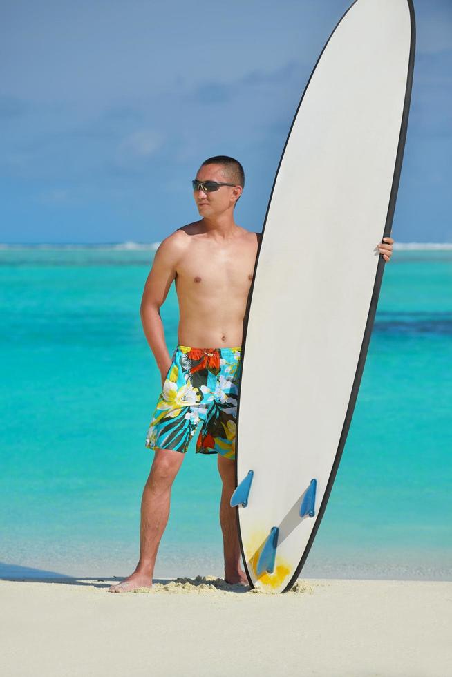 Mann mit Surfbrett am Strand foto