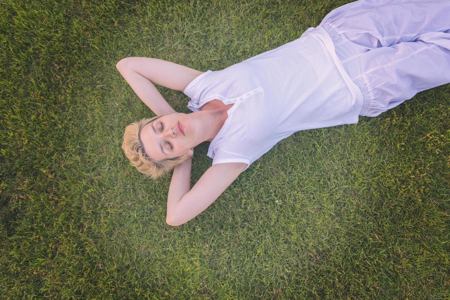 Draufsicht der jungen Frau, die auf dem Gras sich entspannt foto