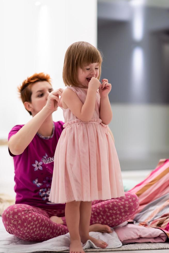 junge mutter hilft tochter beim anziehen eines kleides foto