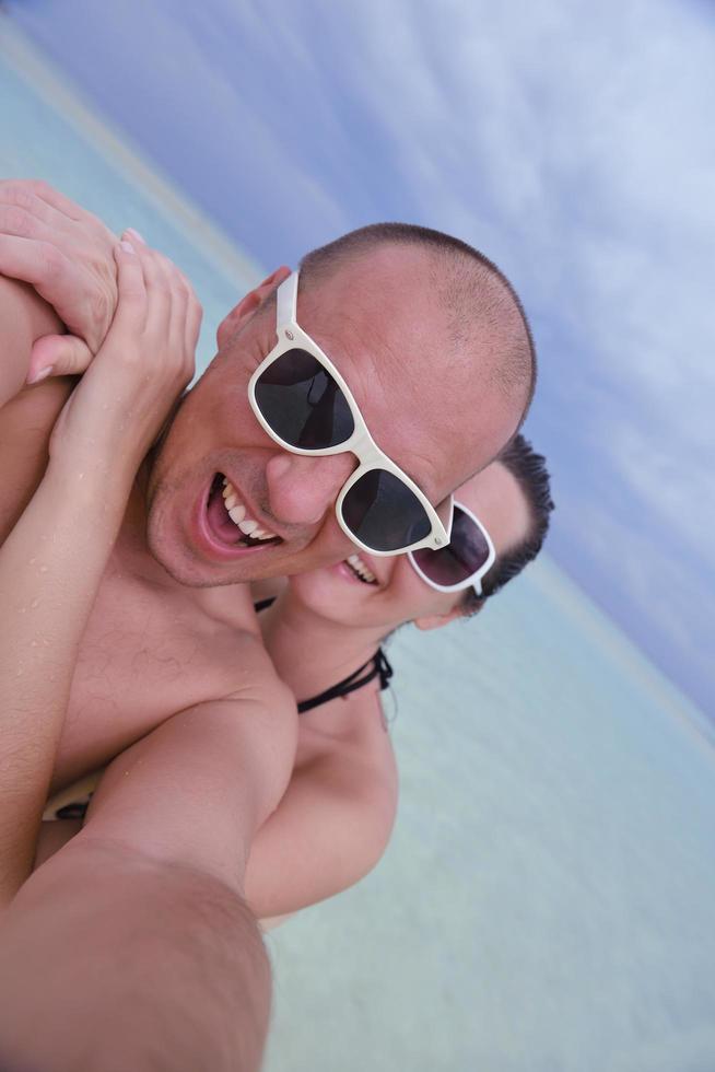 glückliches junges Paar in den Sommerferien hat Spaß und entspannt sich am Strand foto