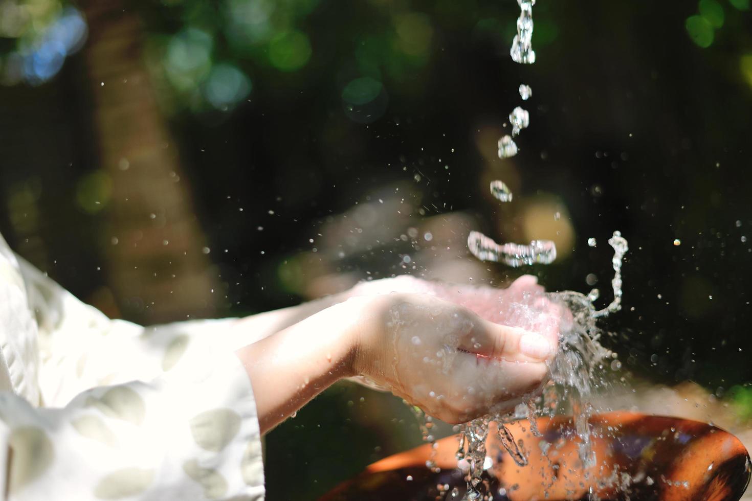 frisches Wasser auf die Hände der Frau spritzen foto