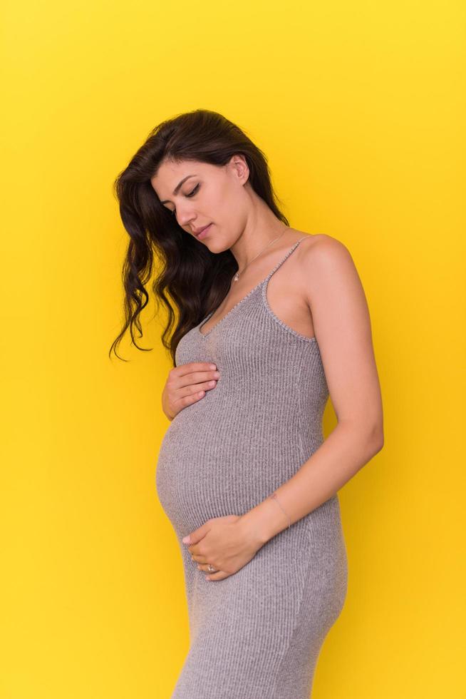 Porträt der schwangeren Frau auf gelbem Hintergrund foto