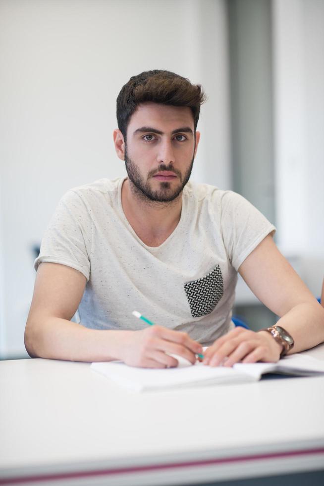 männlicher schüler, der sich im klassenzimmer notizen macht foto