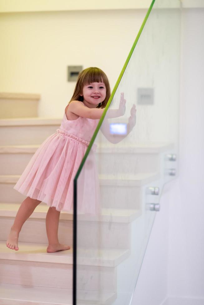 kleines Mädchen, das zu Hause auf der Treppe spielt foto