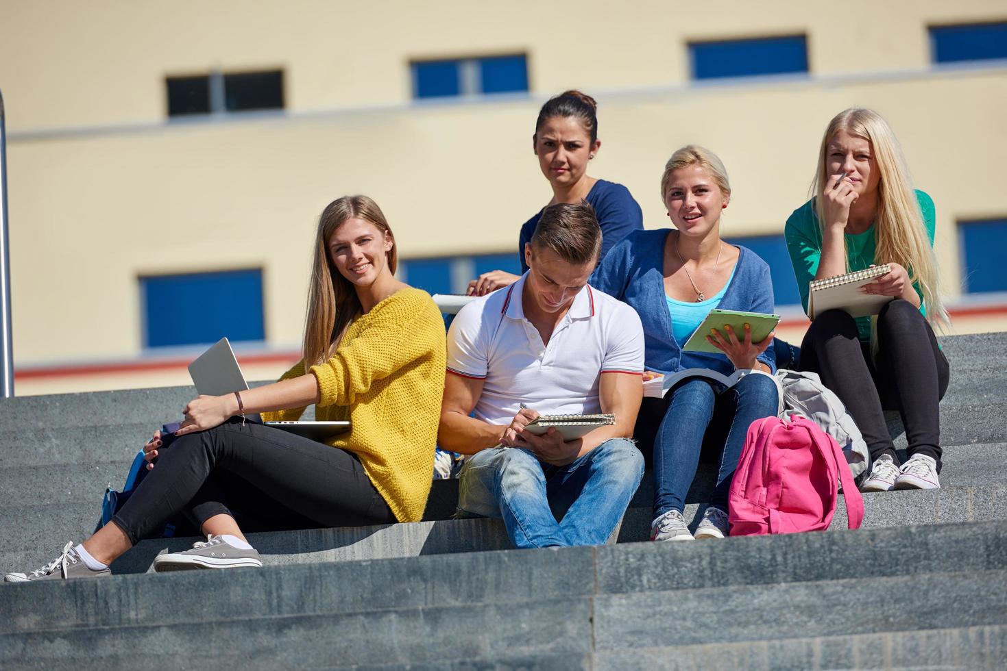 Studenten sitzen draußen auf Stufen foto