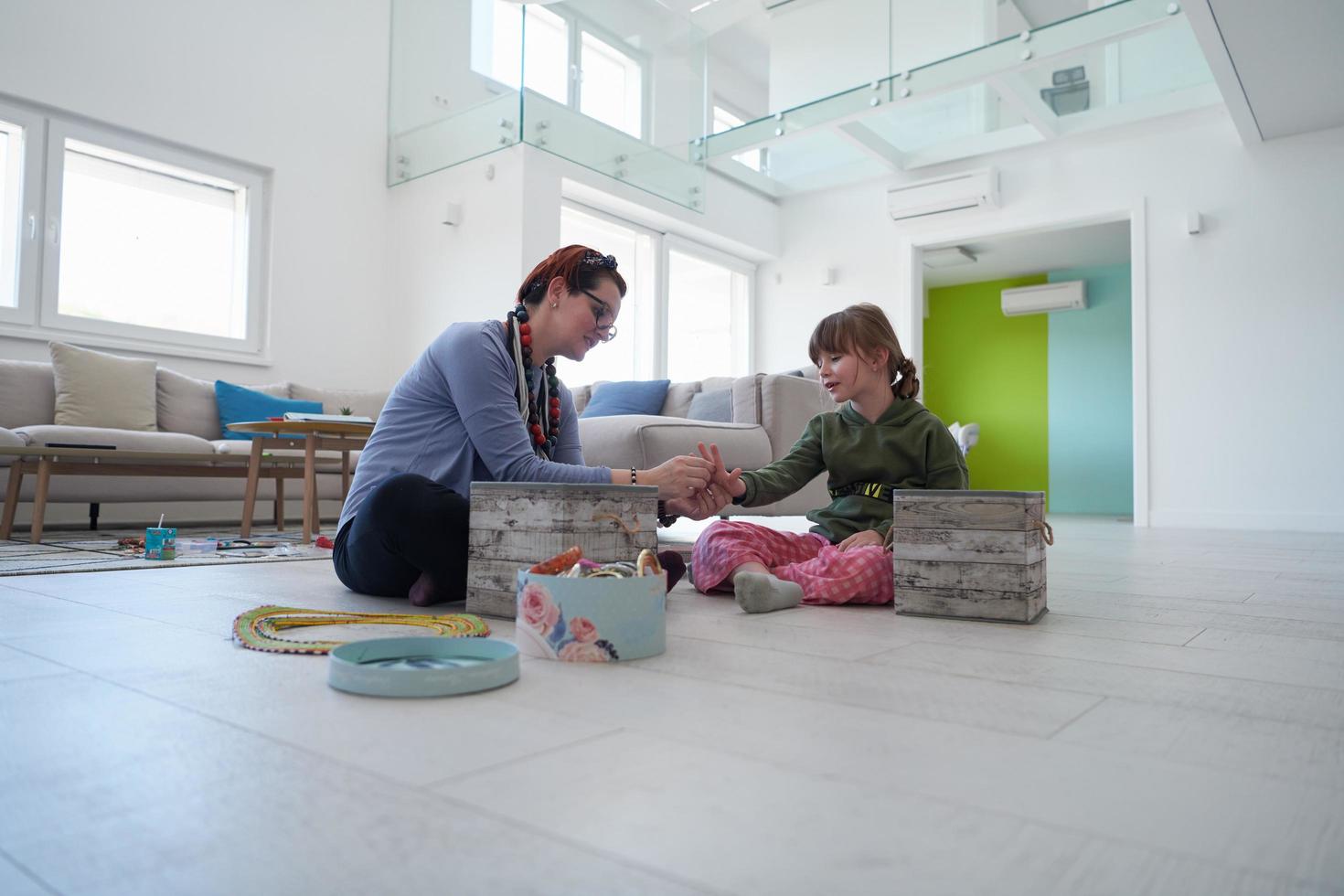 mutter und kleine mädchentochter spielen zu hause mit schmuck foto