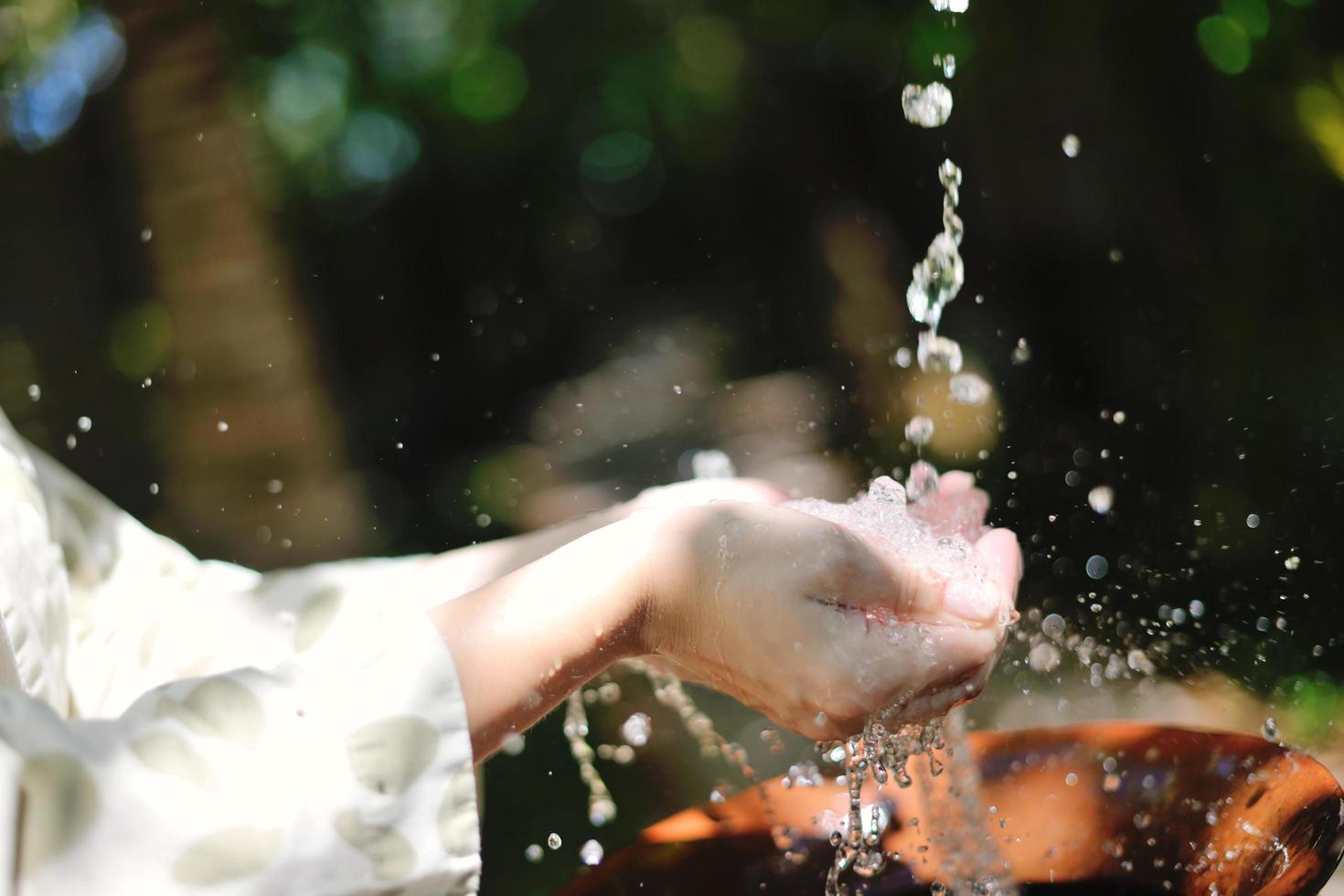 frisches Wasser auf die Hände der Frau spritzen foto