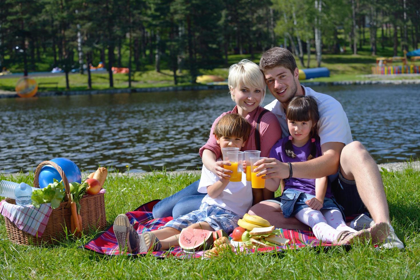 glückliche familie, die zusammen in einem picknick im freien spielt foto