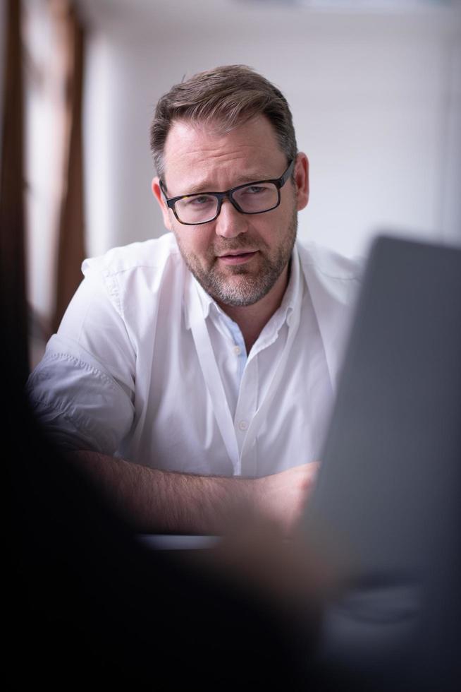 Geschäftsmann schreibt Notizen, während er am Laptop arbeitet foto