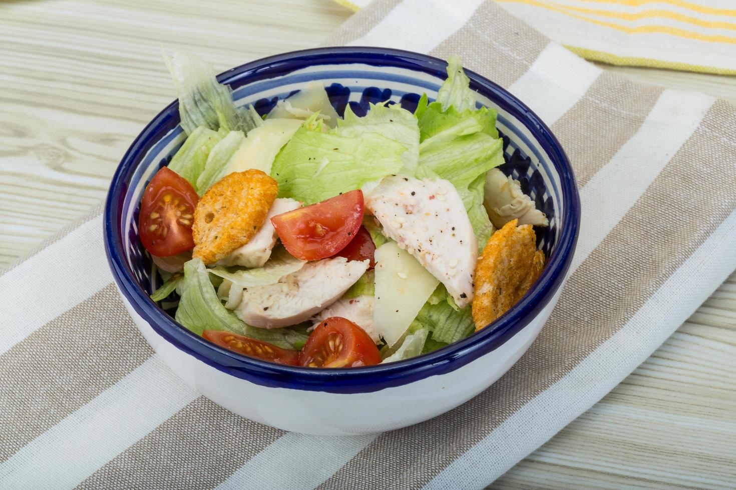 Caesar-Salat mit Hähnchen in einer Schüssel auf Holzhintergrund foto