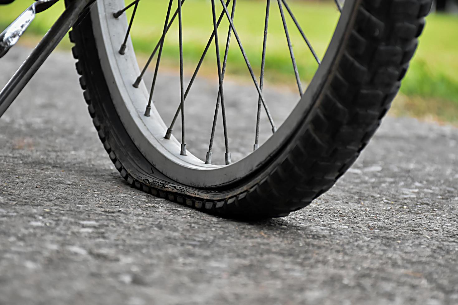 Nahaufnahme des Fahrrads, das einen platten Reifen hat und auf dem Bürgersteig geparkt ist, unscharfer Hintergrund. weicher und selektiver Fokus auf Reifen. foto