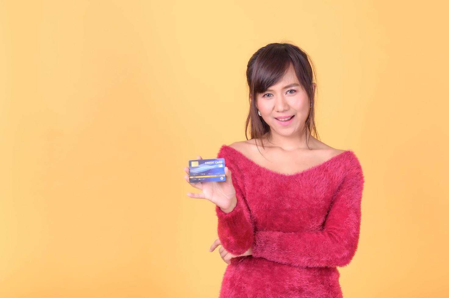 eine schöne asiatische frau ist glücklich und denkt, dass sie mit vielen ihrer kreditkarten ausgeben wird foto