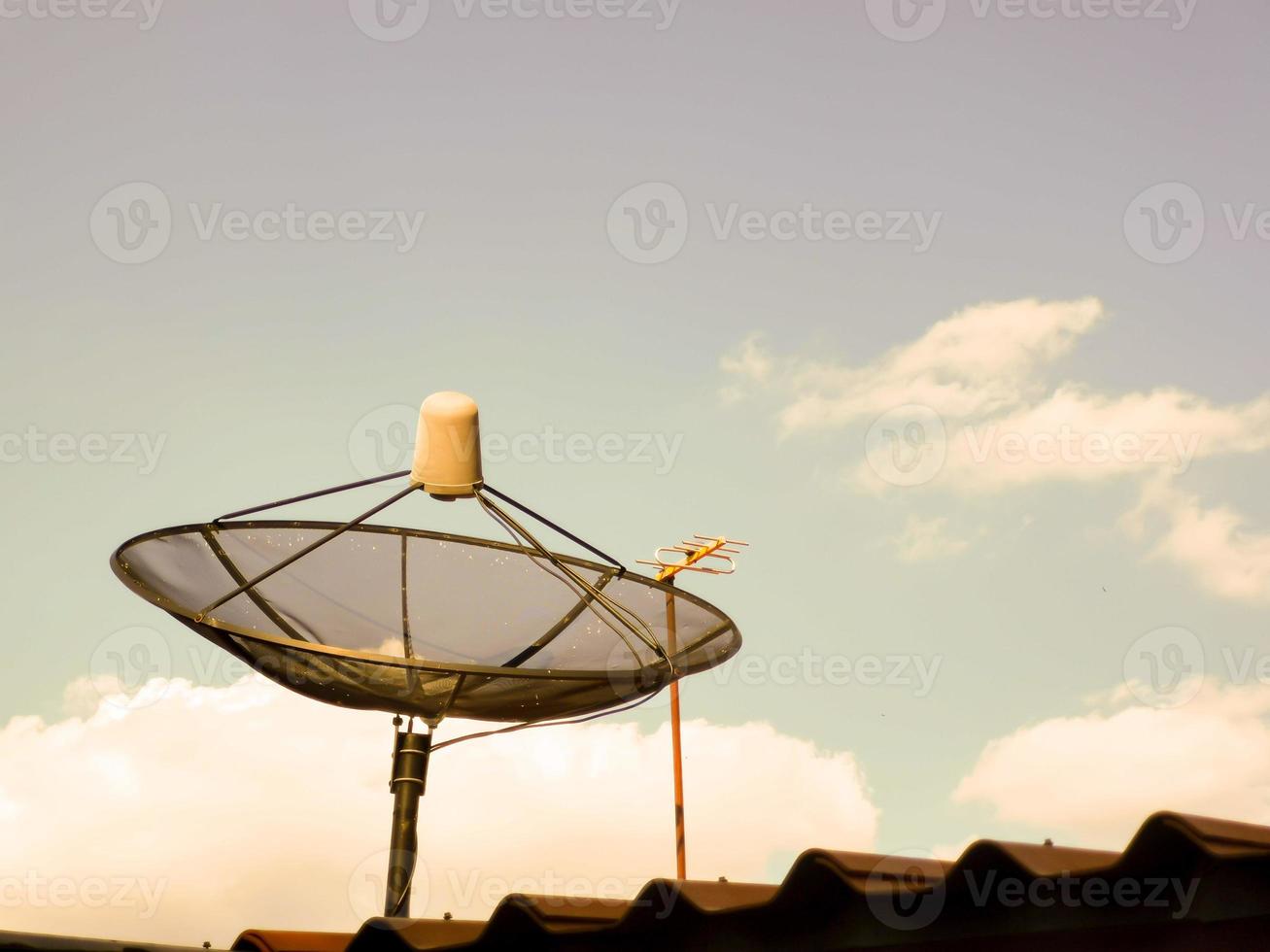 TV-Satellitenschüssel auf dem Dach des Hauses am Abend foto