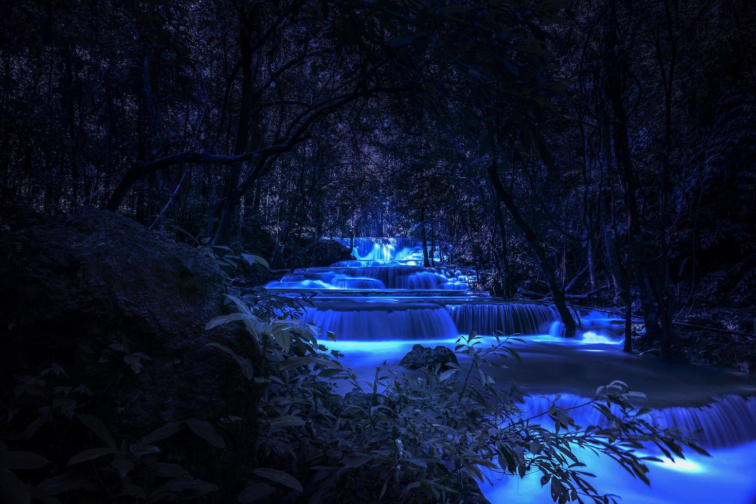 schöne wasserfallnaturlandschaft von bunt in einem tiefen tropischen fantasiedschungel der nacht foto