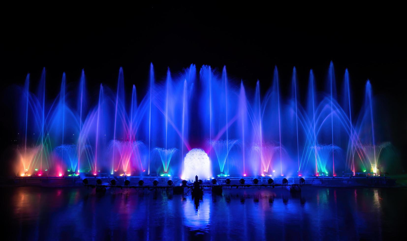 der bunte Springbrunnen tanzt zur Feier des Jahres mit dunklem Nachthimmelhintergrund. foto