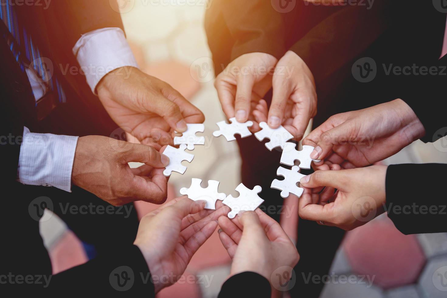 Die Hand eines Geschäftsmannes, der ein Papierpuzzle hält und das Puzzle gemeinsam löst. Das Geschäftsteam setzt ein Puzzle zusammen. eine Unternehmensgruppe, die die Puzzleteile zusammenfügen möchte foto