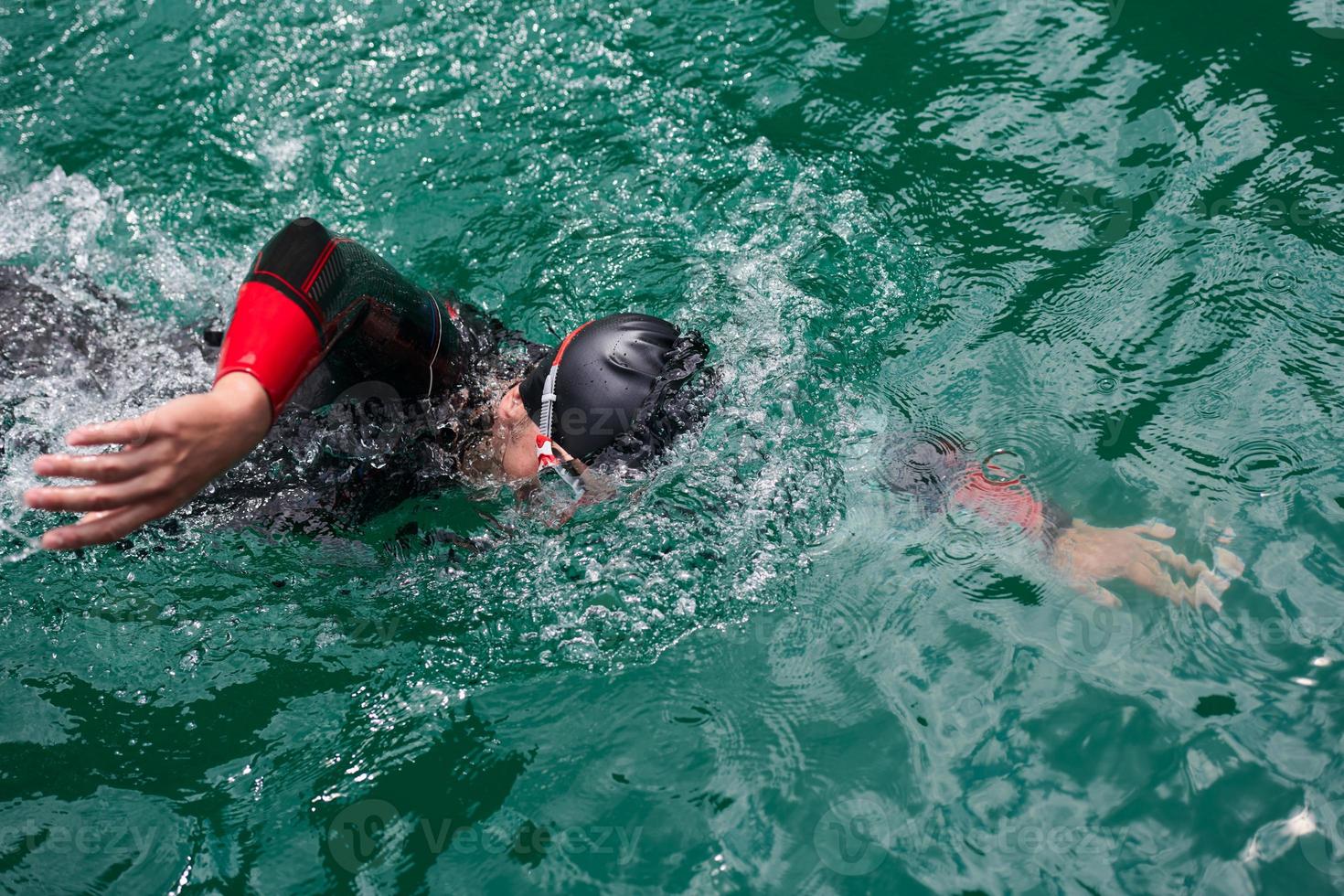 Triathlon-Athlet, der auf dem See schwimmt und einen Neoprenanzug trägt foto