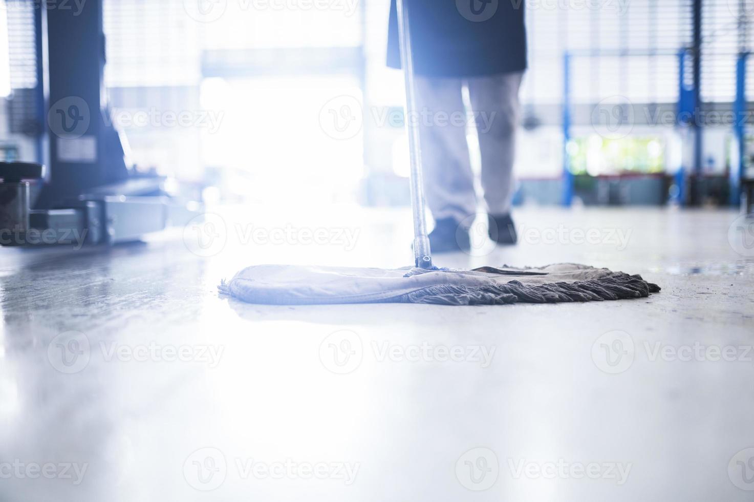 Mechaniker in der Autowerkstatt Reinigung mit einem Wischwasser aus dem Epoxidboden. in der Autowerkstatt foto