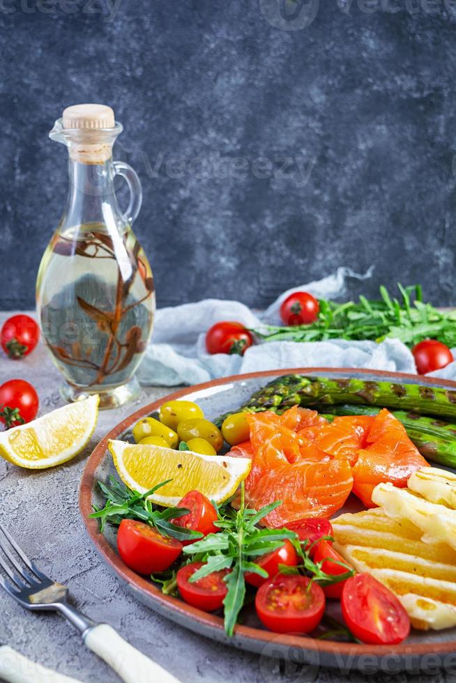 Salat mit Spargel, gegrilltem Halloumi-Käse, Lachsfilet, Tomaten, Rucola und grünen Oliven foto