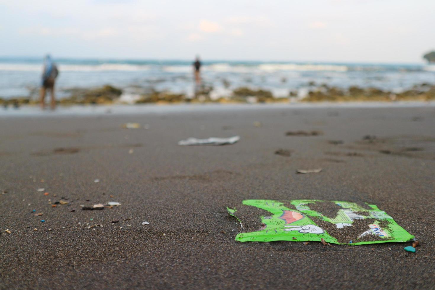 verschütteter Müll am Strand der Großstadt. leerer gebrauchter schmutziger Kunststoff. schmutziges meer sandiges ufer der indische ozean. Umweltverschmutzung. ökologisches Problem. Bokeh bewegte Wellen im Hintergrund foto