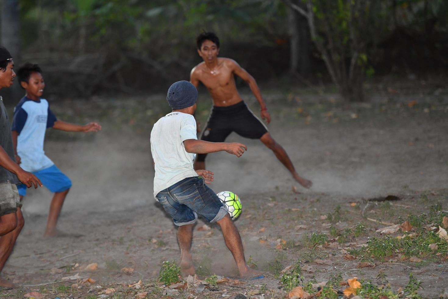 gili asahan, indonesien - august 22 2016 - jungen spielen fußball bei sonnenuntergang auf einem palmenfeld in der nähe des strandes foto