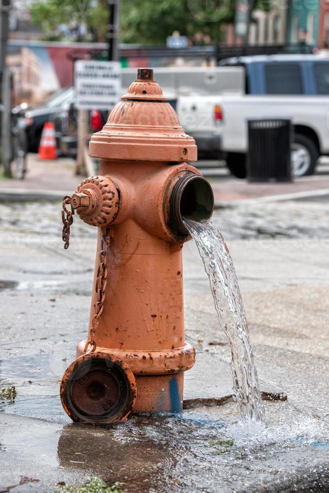 Straße orangefarbener Hydrant, der Wasser auf der Straße verteilt foto