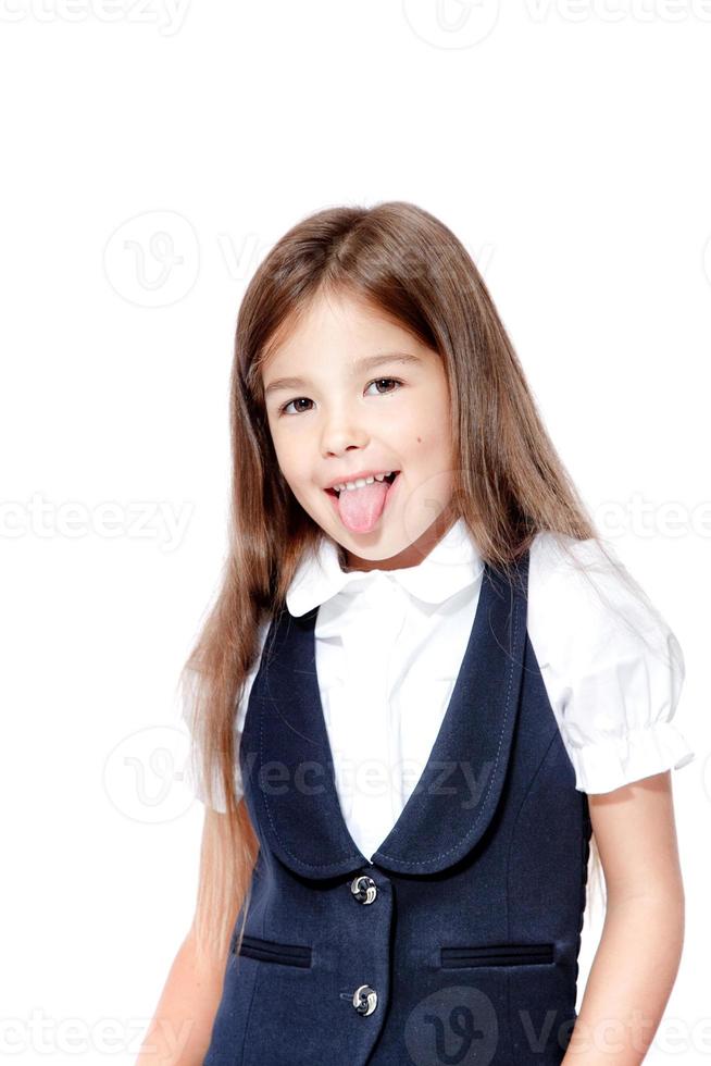 Portrait von niedlichen lächelnden Schulmädchen zeigt Zunge, isoliert auf weißem Hintergrund. foto