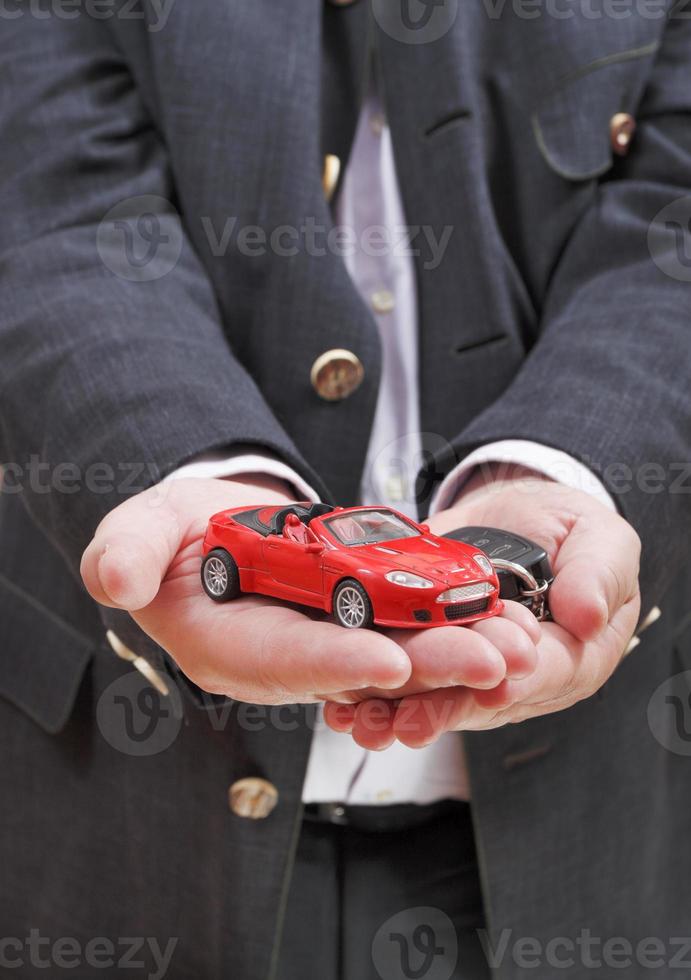 rotes Auto und Schlüssel in der Hand des Verkäufers foto