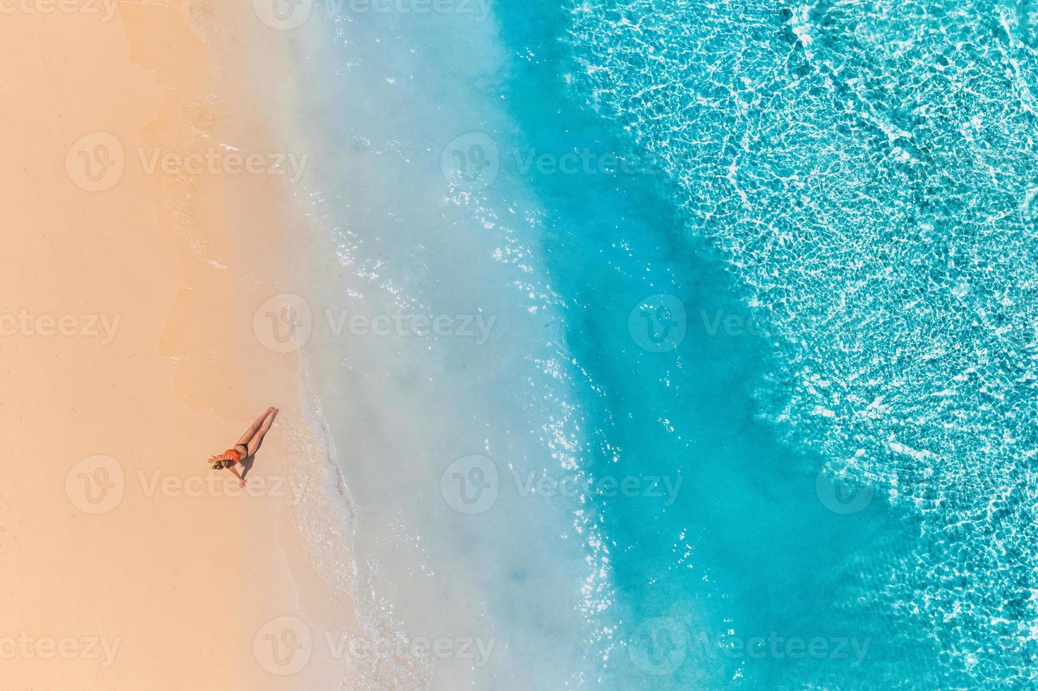 Luftaufnahme einer Frau am Strand in einem Bikini liegend und sonnenbadend. perfekte wellen, spritzer entspannender sommer freiheit luxus lebensstil foto