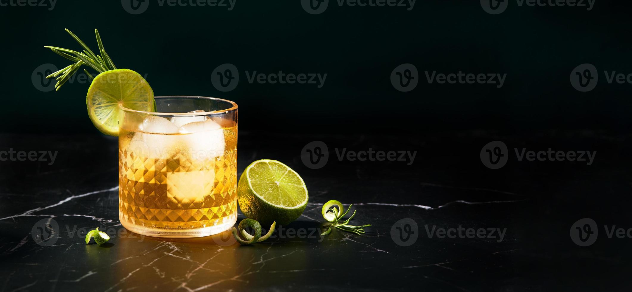 Alkoholischer oder alkoholfreier Cocktail mit Limette und Rosmarin auf dunklem Marmortisch foto
