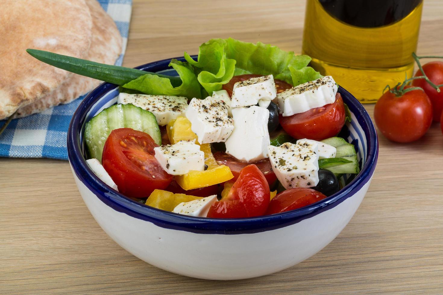 griechischer salat in einer schüssel auf holzhintergrund foto