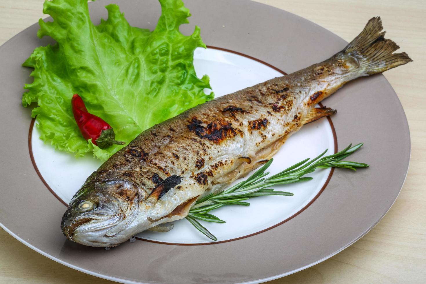 Gegrillte Forelle auf dem Teller und Holzhintergrund foto