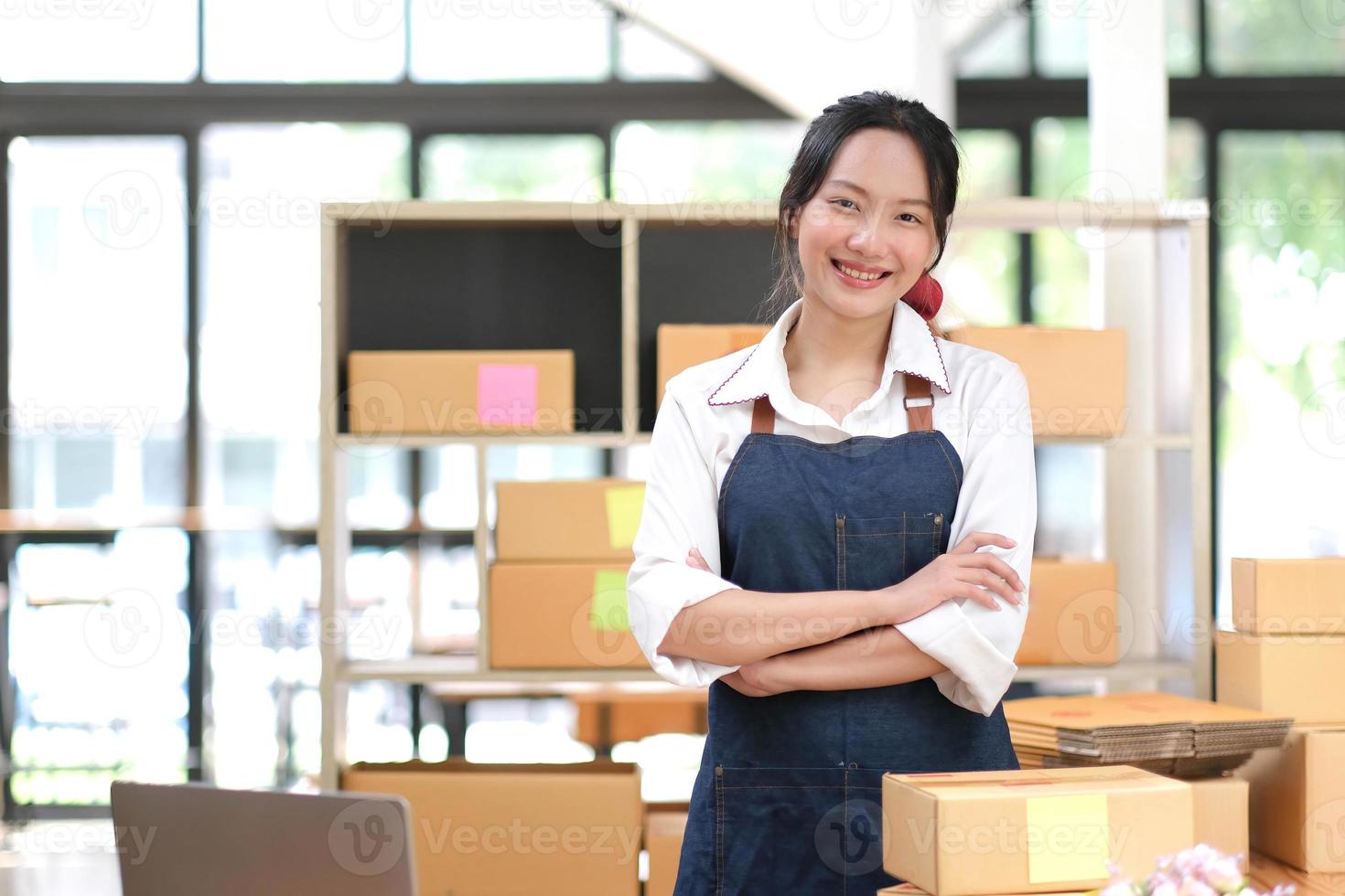 Porträt einer asiatischen jungen Frau, die zu Hause mit einer Kiste am Arbeitsplatz arbeitet. Start-up-Kleinunternehmer, Kleinunternehmer-KMU oder freiberufliches Online- und Lieferkonzept. foto