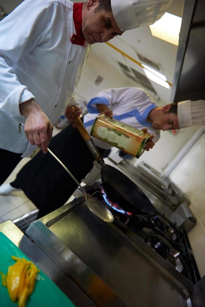 koch in der hotelküche bereitet essen mit feuer zu foto