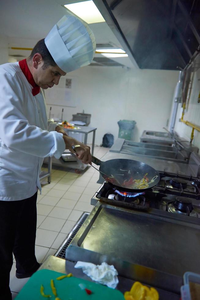 koch in der hotelküche bereitet essen mit feuer zu foto