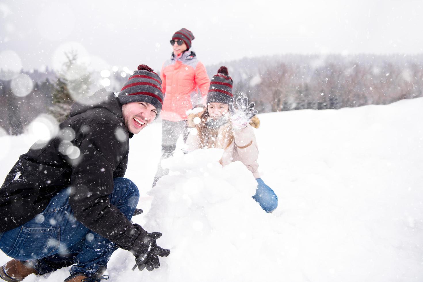 Gruppe junger Leute, die einen Schneemann bauen foto