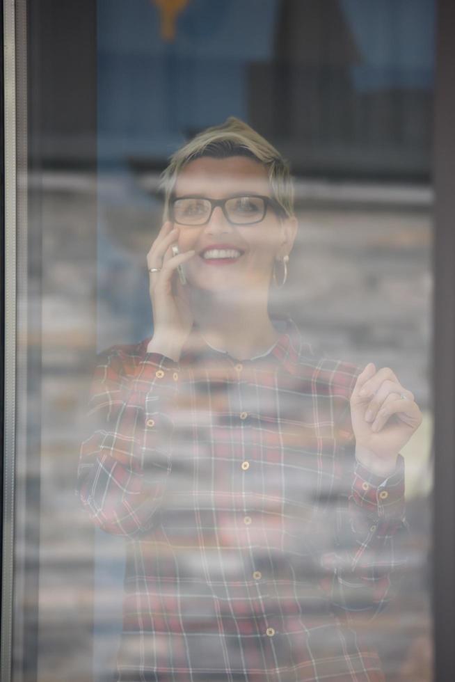 Geschäftsfrau im Büro, die per Telefonteam über das Treffen im Hintergrund spricht foto