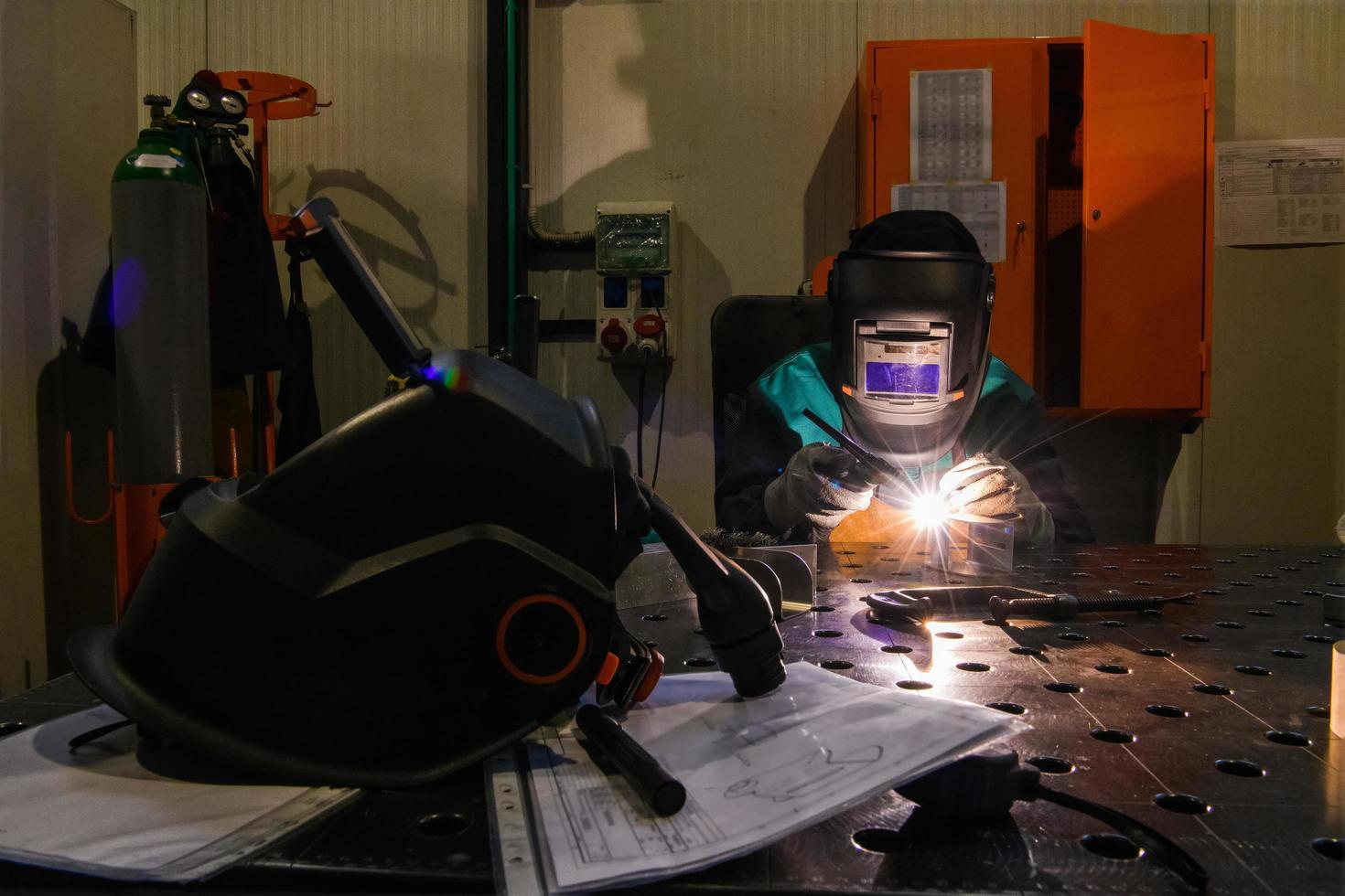 Professioneller Schweißer führt Arbeiten mit Metallteilen in der Fabrik, Funken und Strom durch. Banner für Industriearbeiter. foto