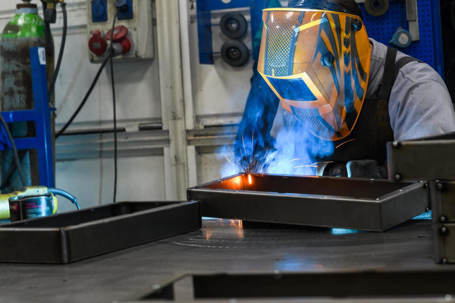 Professioneller Schweißer führt Arbeiten mit Metallteilen in der Fabrik, Funken und Strom durch. Banner für Industriearbeiter. foto