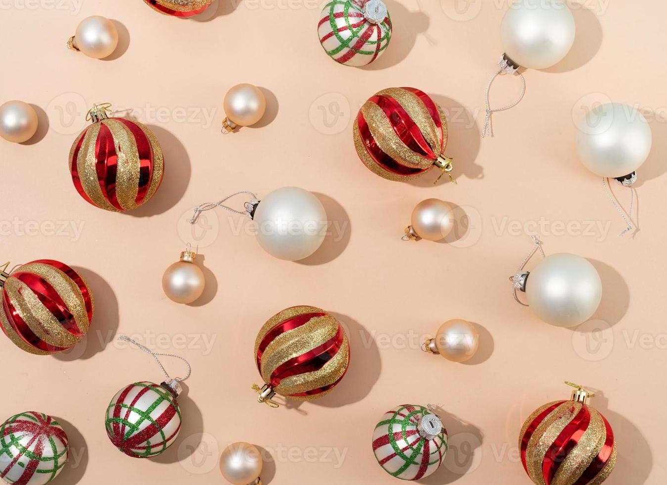 rote und weiße glänzende weihnachtskugeln auf beigem pastellhintergrund, muster foto