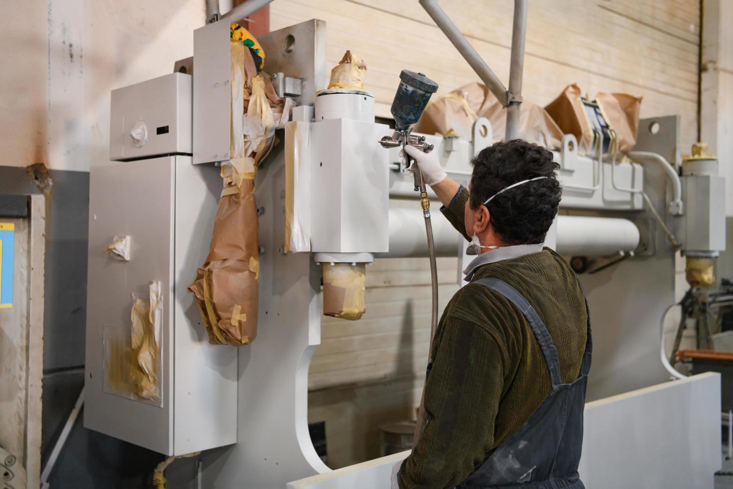 ein Arbeiter, der mit Airless-Spray auf ein mechanisches Teil malt foto