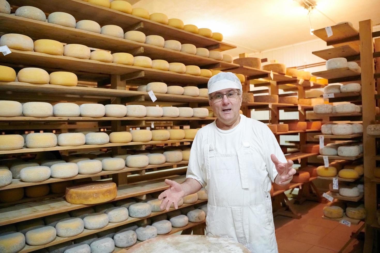 Käser am Lager mit Regalen voller Kuh- und Ziegenkäse foto