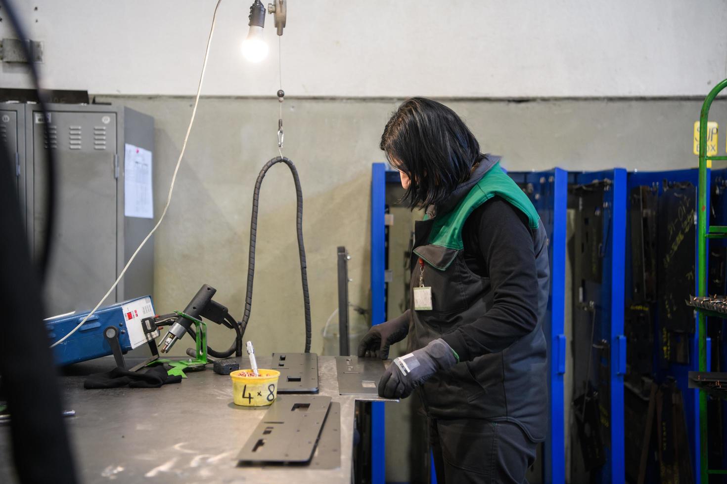 eine frau, die in der modernen metallerzeugungs- und -verarbeitungsindustrie arbeitet, schweißt das produkt und bereitet es für eine cnc-maschine vor foto