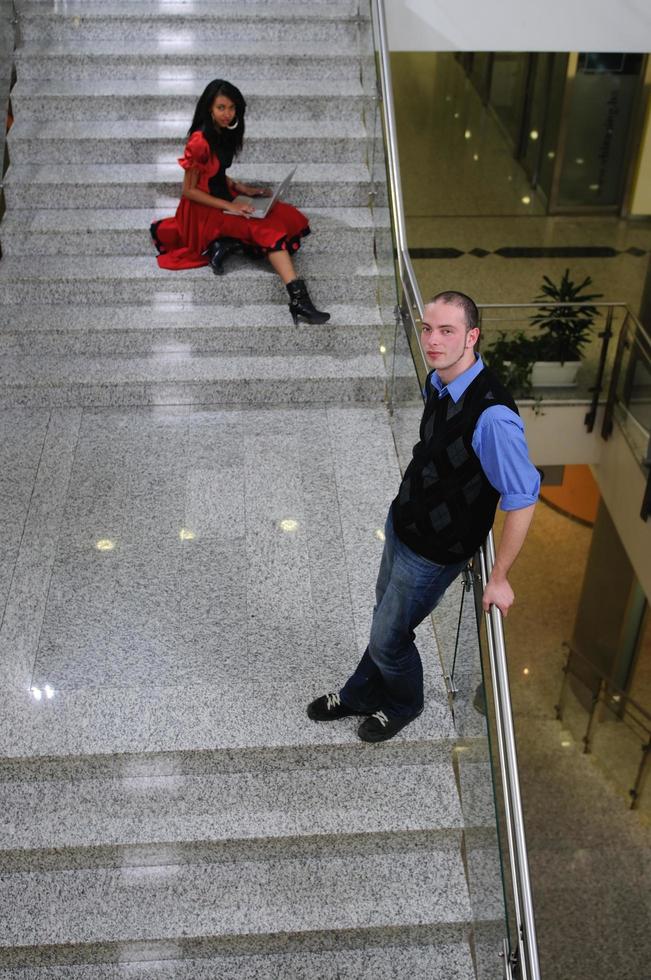 junger geschäftsmann, der auf treppe steht und laptop hält foto