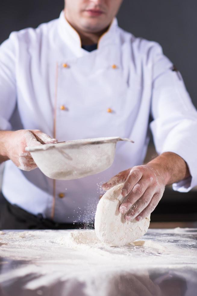 Küchenchef streut Mehl über frischen Pizzateig foto