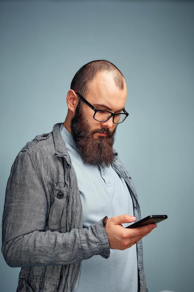 lebensstilgrübelnder mann mit bart und telefon, hintergrund, copyspace. foto