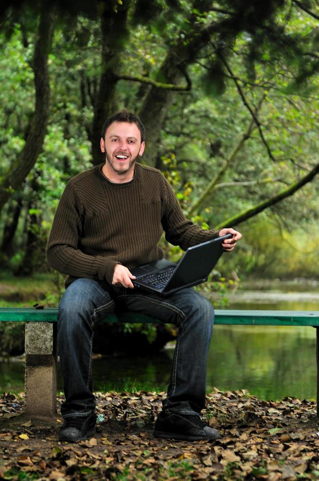 Junger Geschäftsmann, der am Laptop im Freien arbeitet foto