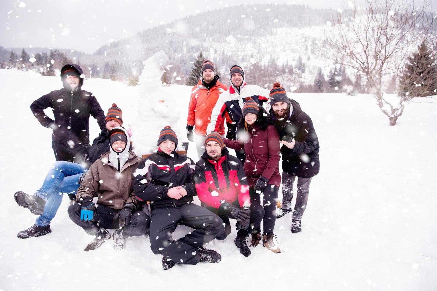 gruppenporträt von jungen leuten, die mit schneemann posieren foto